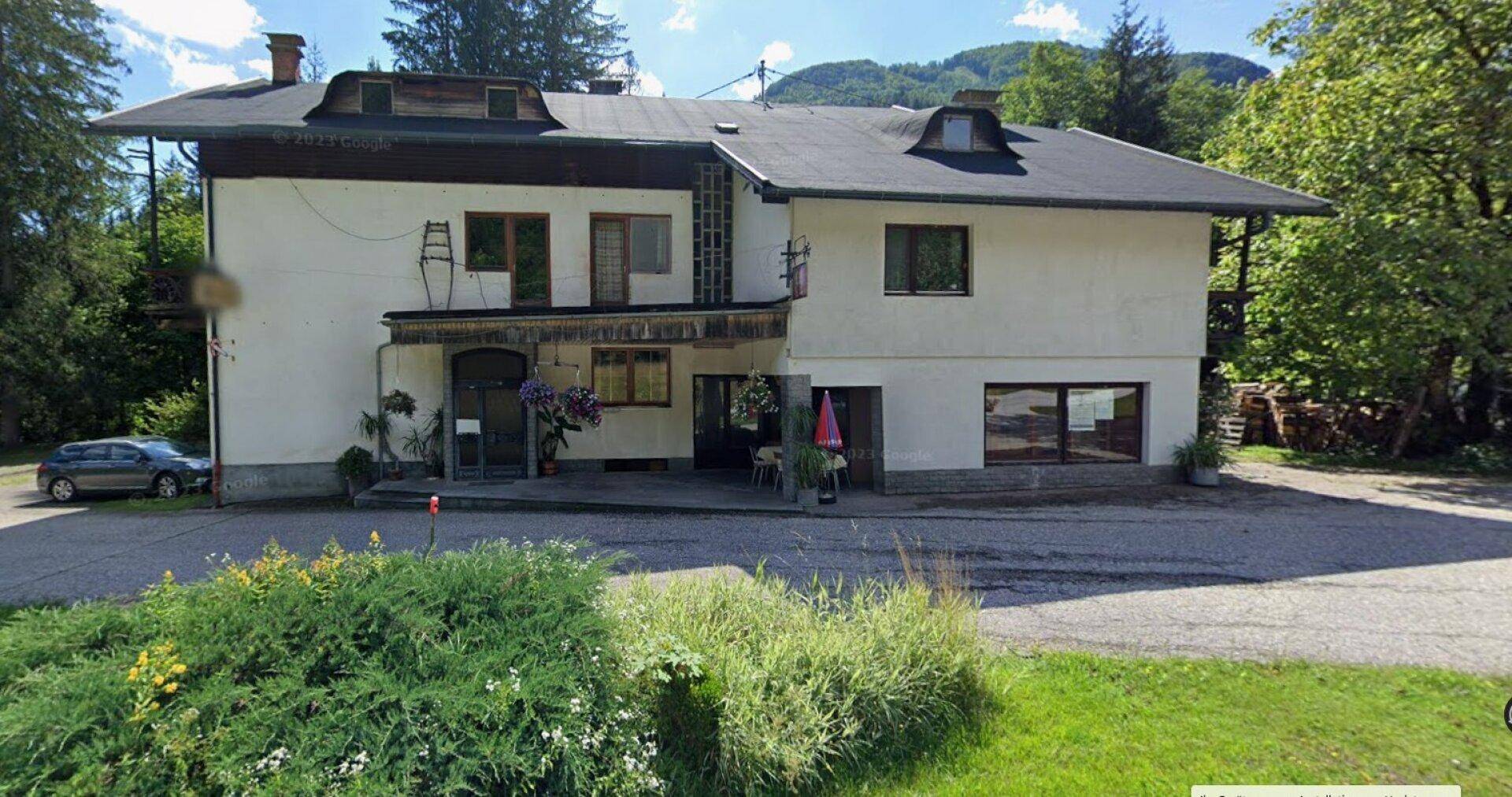 Ansicht des traditionellen Gebäudes von der Straße mit umliegender Natur und Bäumen.