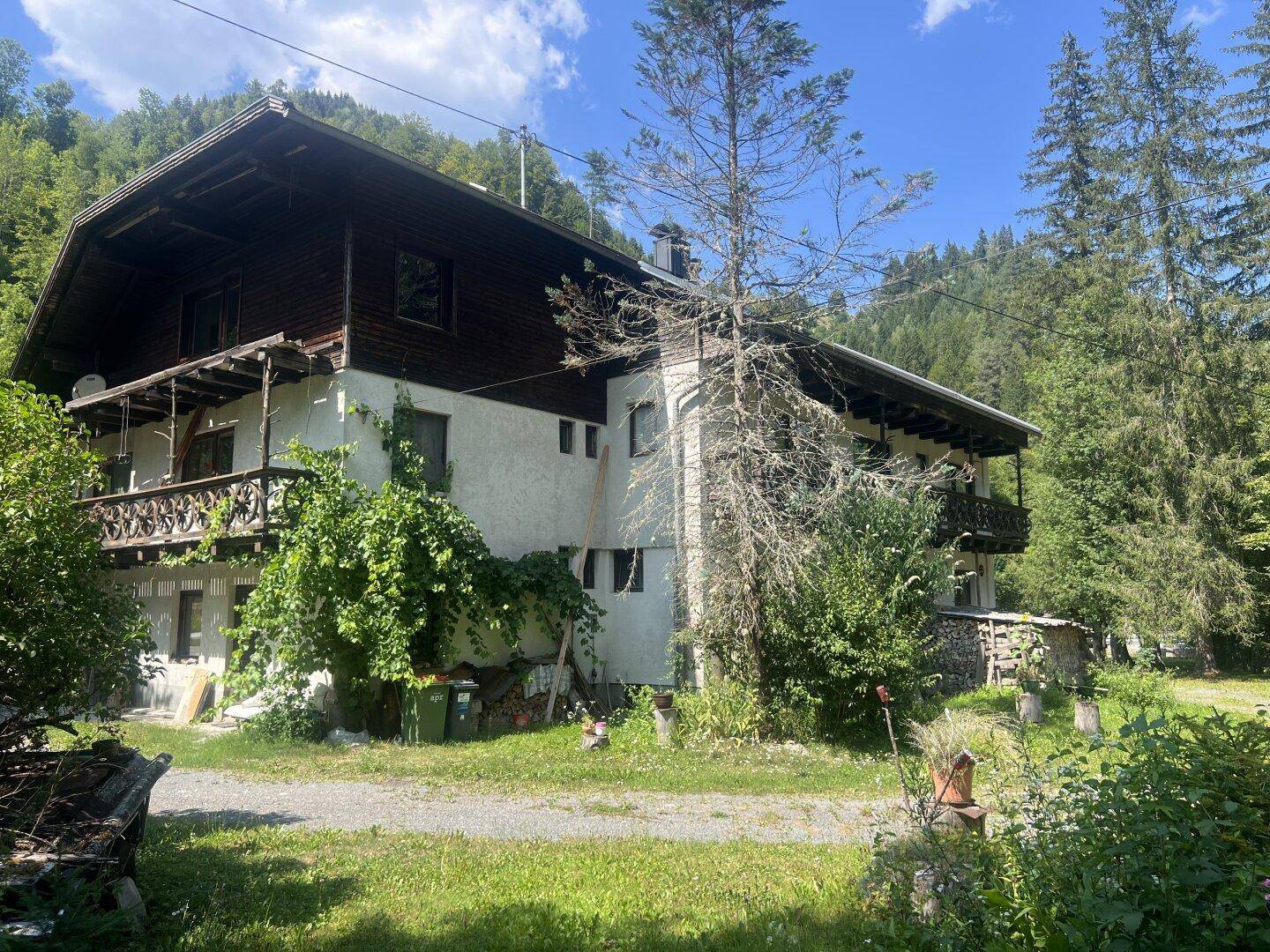 Rückansicht des Gebäudes mit Holzbalkonen und üppiger Vegetation im Gartenbereich.