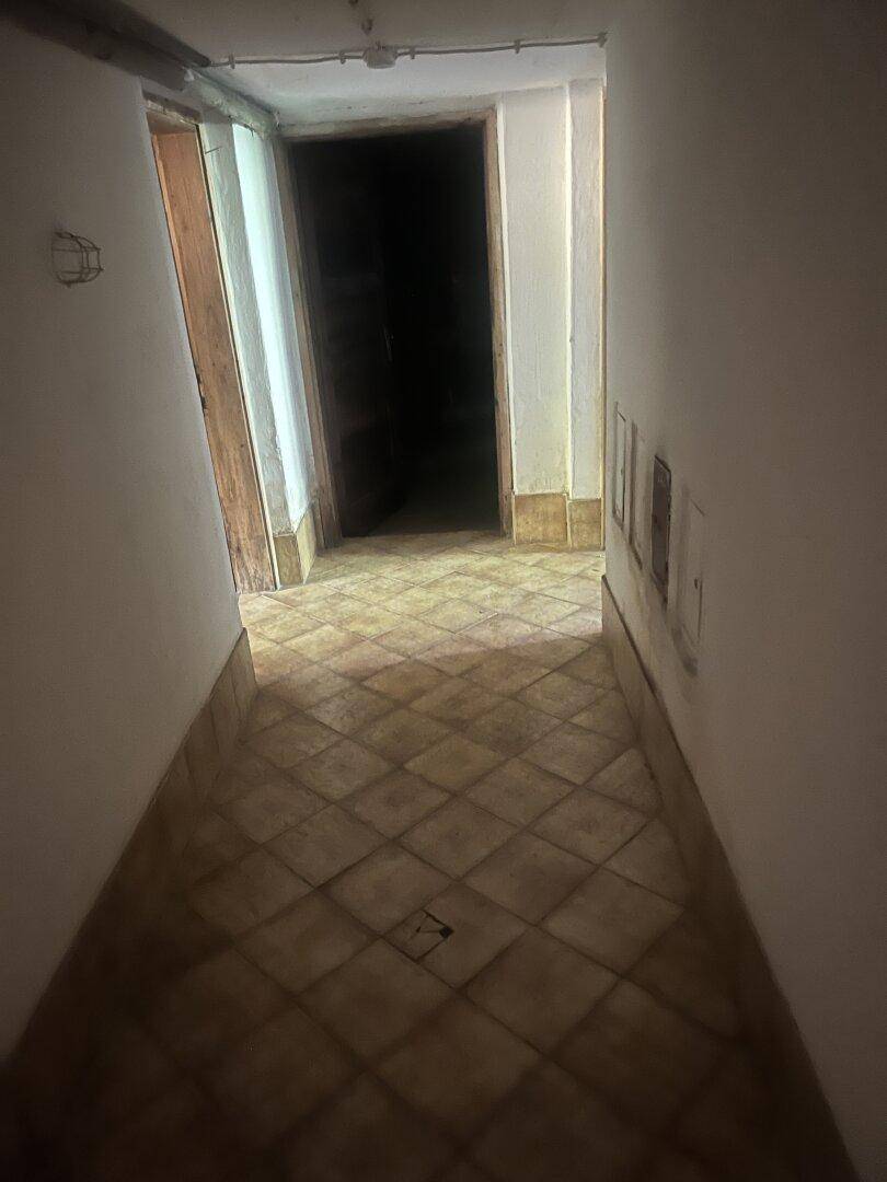 Langer, gefliester Flur im Untergeschoss mit Zugang zu verschiedenen Räumen.