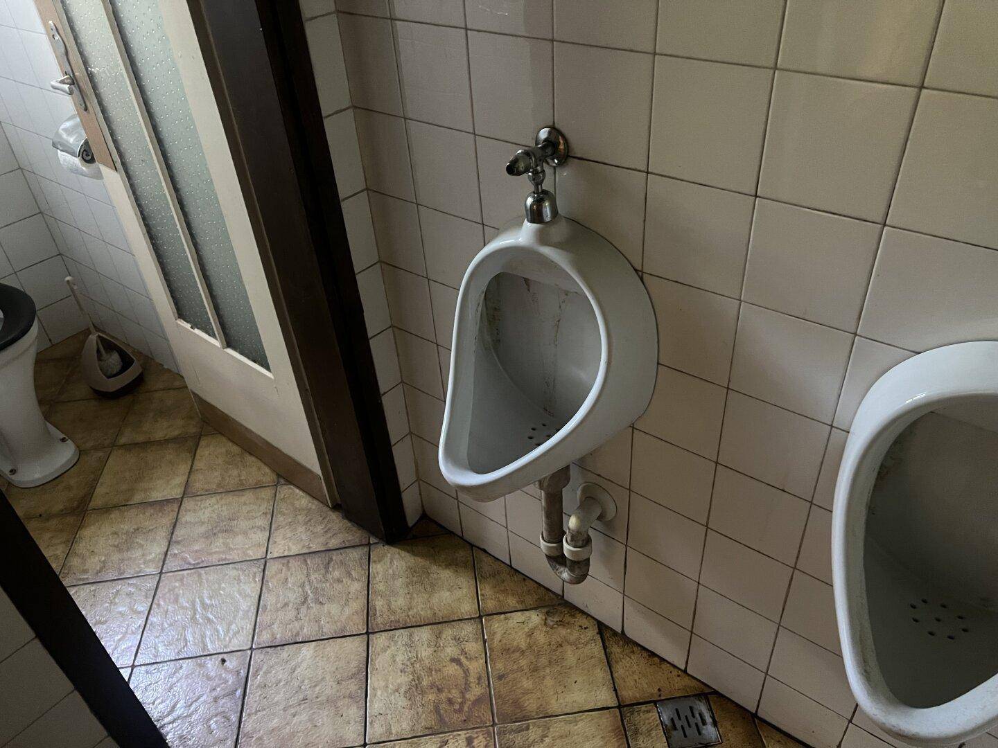 Toilettenraum mit Urinalen und gefliesten Wänden und Böden.