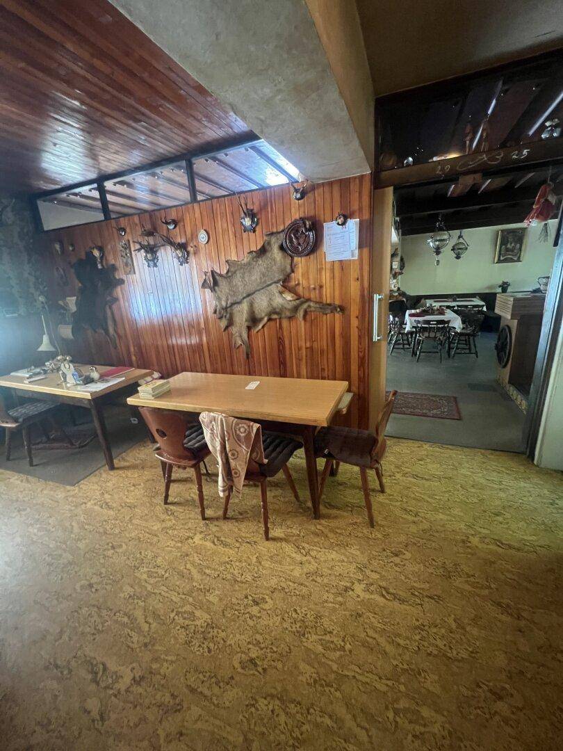 Rustikaler Essbereich mit Holztischen, Holzvertäfelung und traditioneller Jagddekoration.