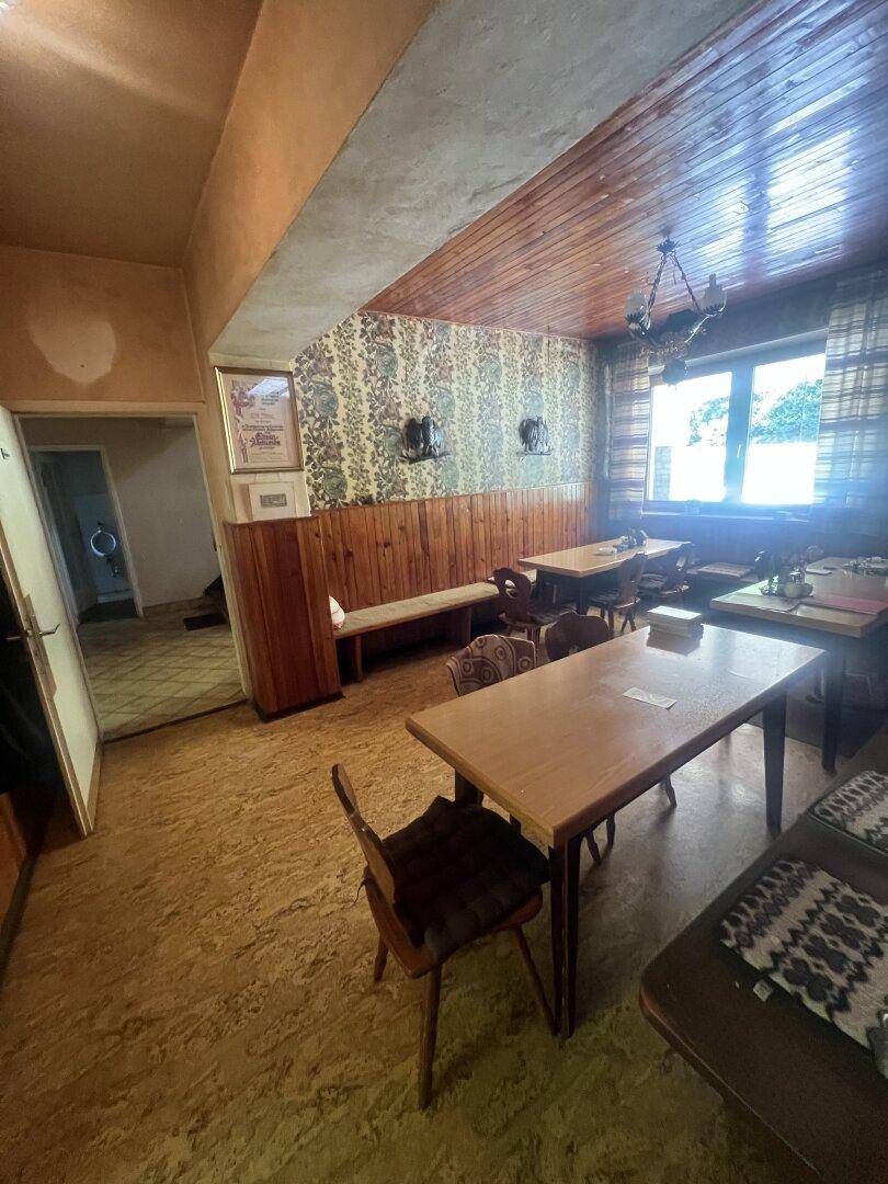Traditioneller Essbereich mit Holztischen, gemusterter Tapete und Holzdecke.