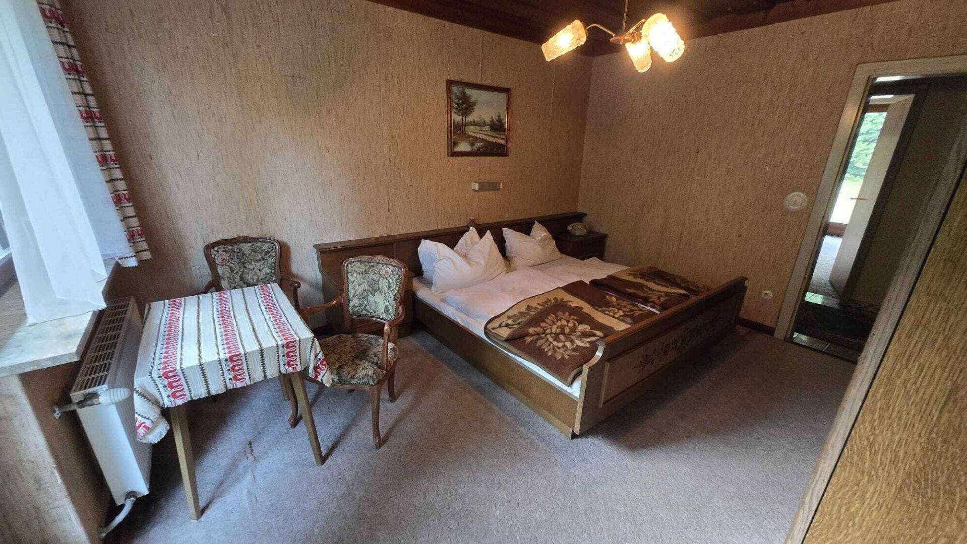 Gemütliches Schlafzimmer mit Doppelbett, Teppichboden und traditioneller Holzdecke sowie Tapeten.