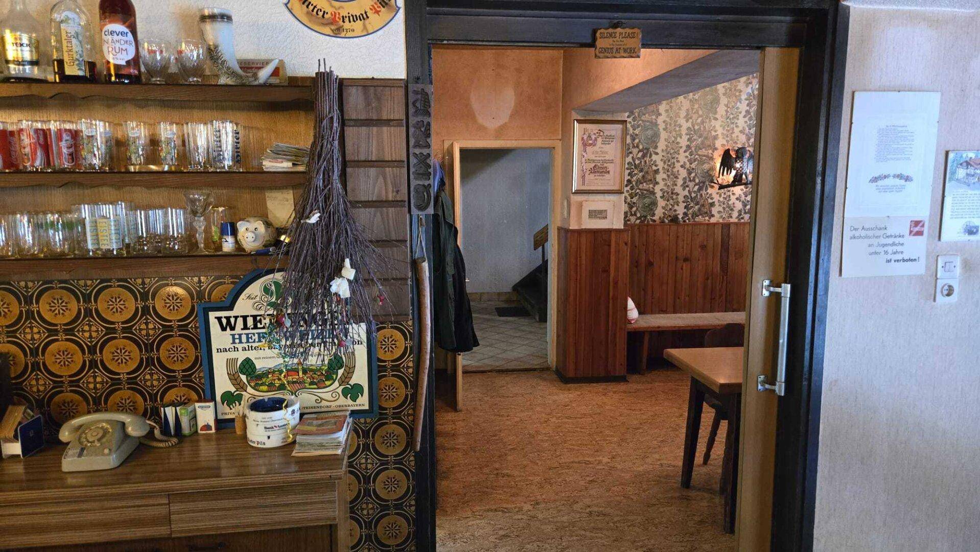 Traditioneller Innenraum mit Theke, Gläsern und Durchgang zu weiteren Räumen im Landhausstil.