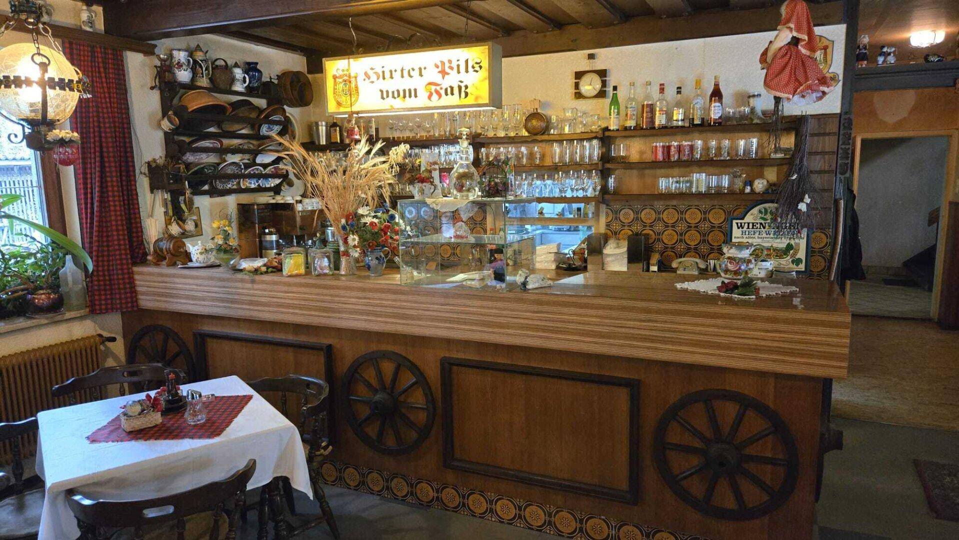 Rustikale Bar mit Theke, gefüllten Regalen und traditioneller Dekoration im Alpenstil.