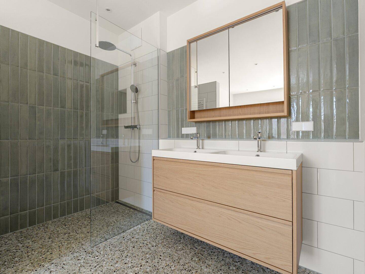 Modernes Badezimmer mit Doppelwaschbecken, begehbarer Dusche und grauen Fliesen.