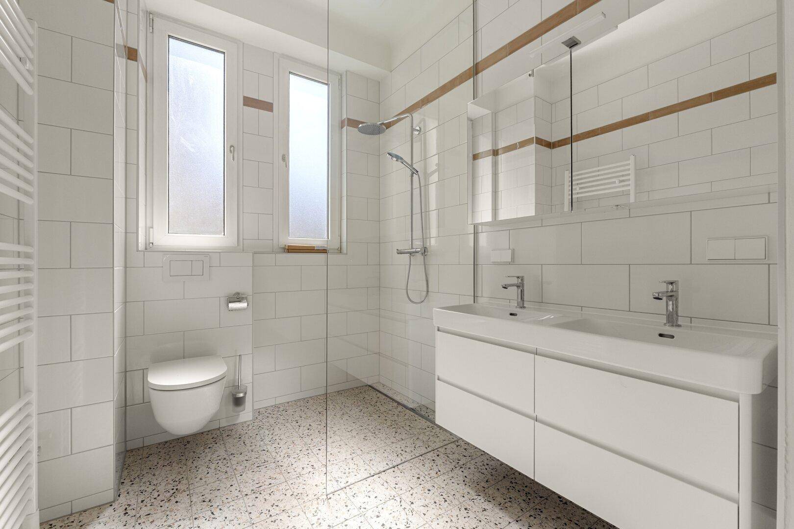 Modernes Badezimmer mit weißen Fliesen, begehbarer Dusche, Doppelwaschbecken und Fenster.