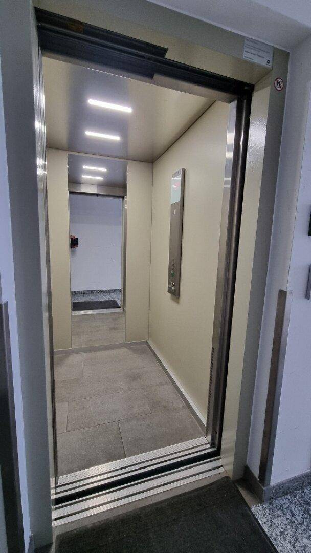 Moderner Aufzug mit Edelstahloberflächen und LED-Beleuchtung, sauber und funktional für den Transport.