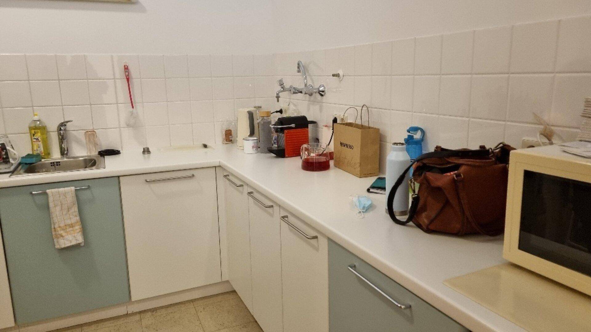 Kleine Küche mit weißen und hellblauen Schränken, Fliesenrückwand und Spülbecken, praktisch ausgestattet.