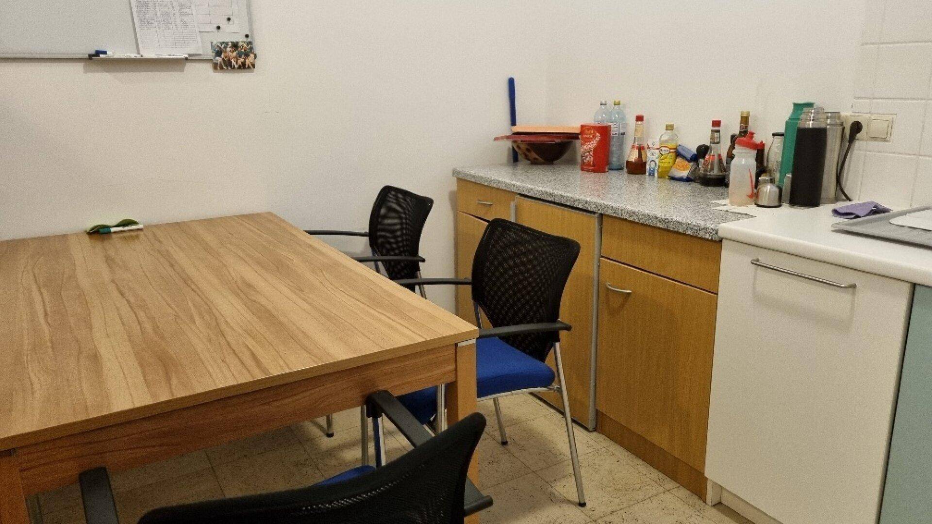 Essbereich in der Küche mit Holztisch, Bürostühlen und Arbeitsplatte mit Granitoptik, gemütlich und funktional.