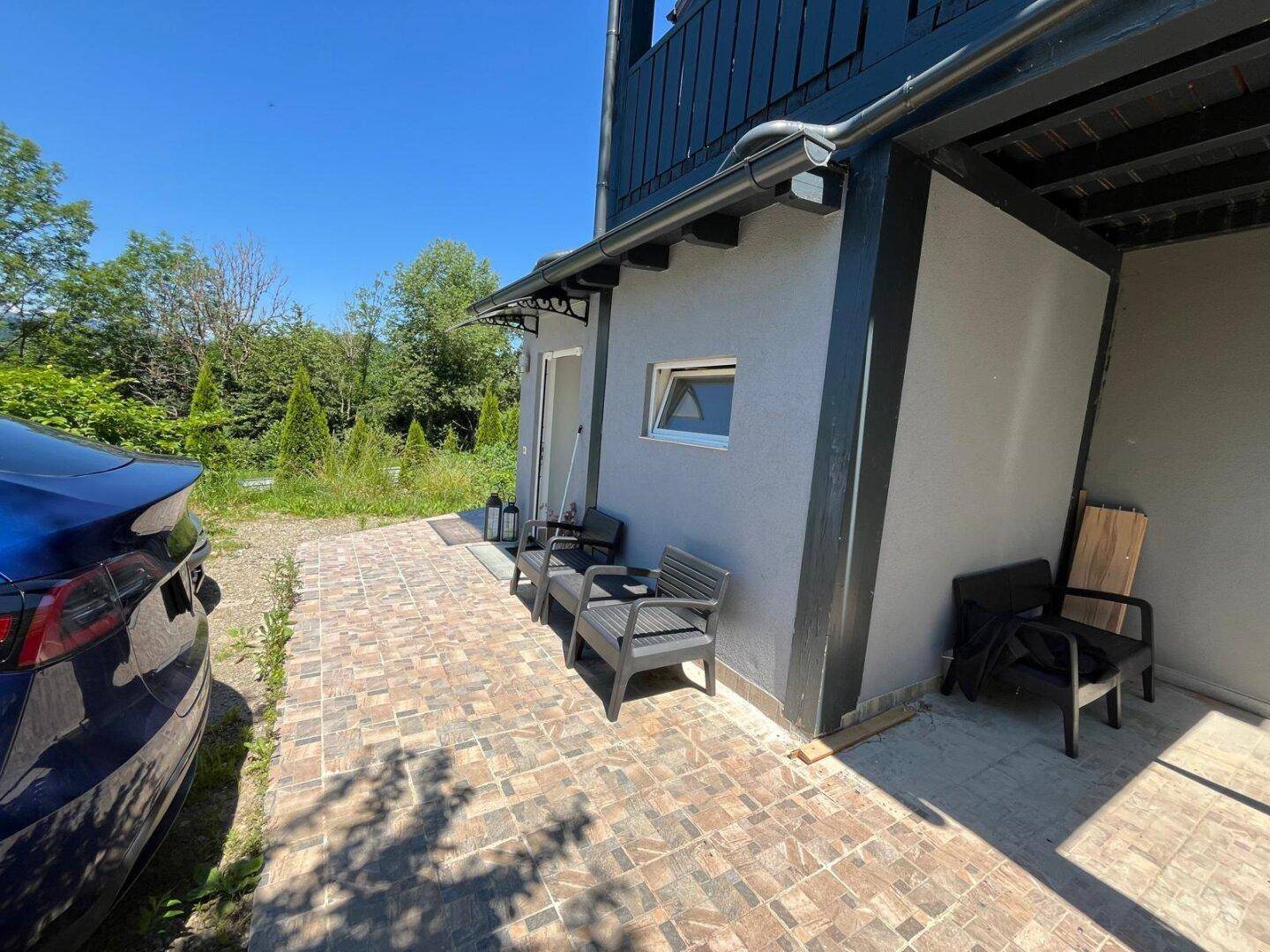Eingangsbereich des Hauses mit gepflastertem Vorplatz und einem geparkten Auto.