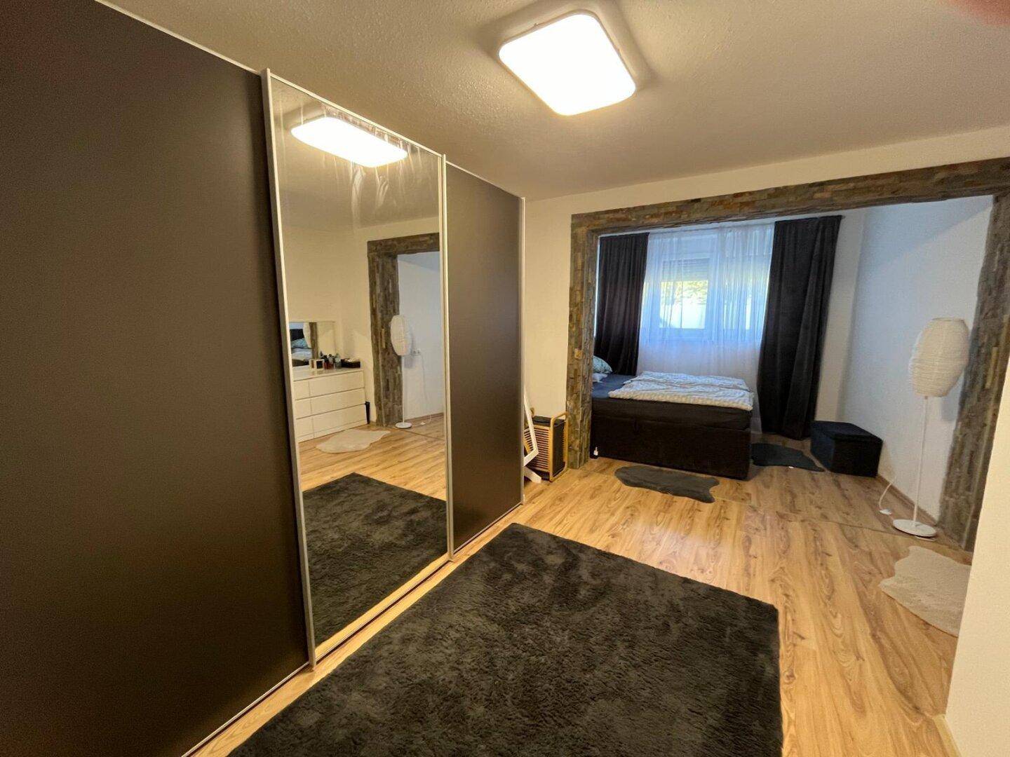 Geräumiges Schlafzimmer mit großem Spiegelschrank und Holzfußboden, der den Raum hell und offen wirken lässt.