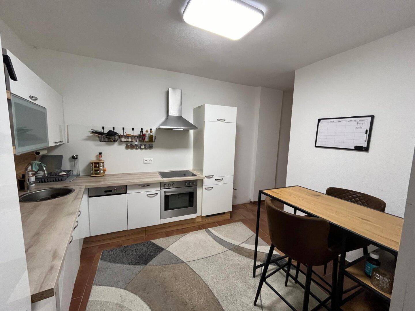 Moderne Einbauküche mit weißen Fronten, integriertem Backofen und Dunstabzugshaube, ideal für den täglichen Gebrauch.