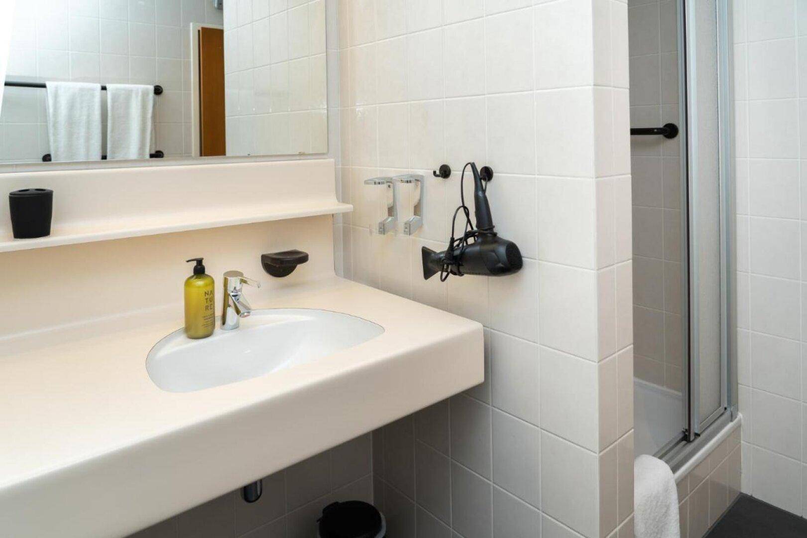Modernes Badezimmer mit Fliesen, Einzelwaschbecken und Duschkabine.