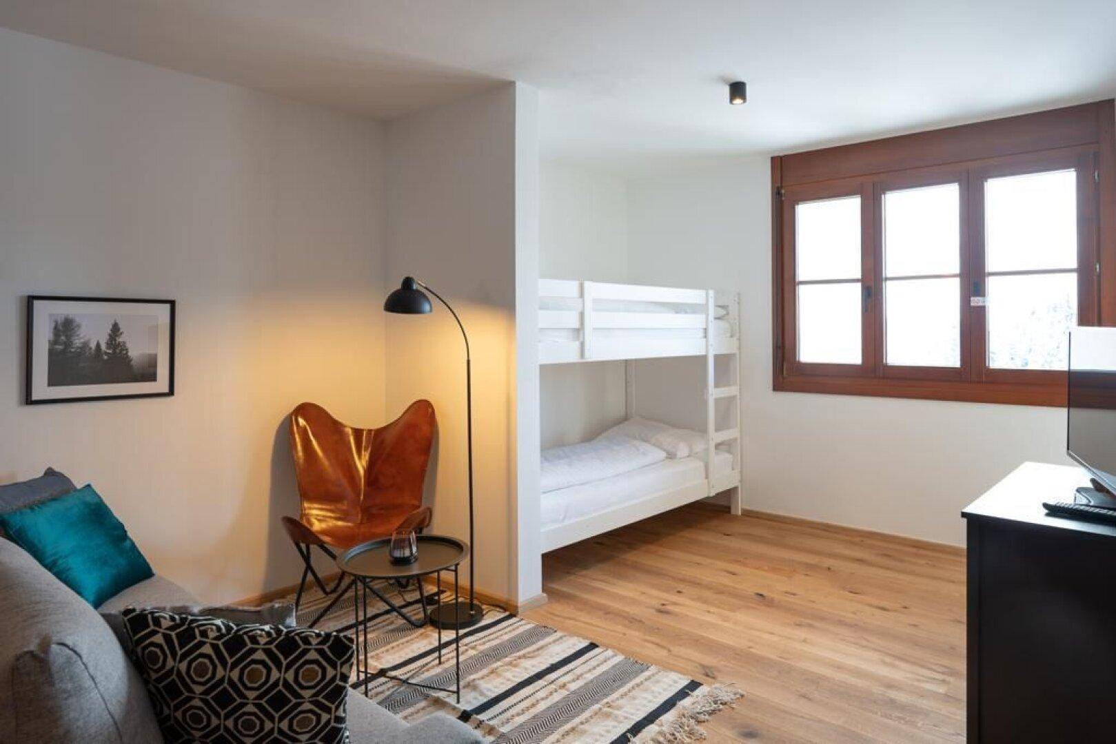 Gemütlicher Wohnbereich mit Sofa, Etagenbett und einem bequemen Ledersessel.