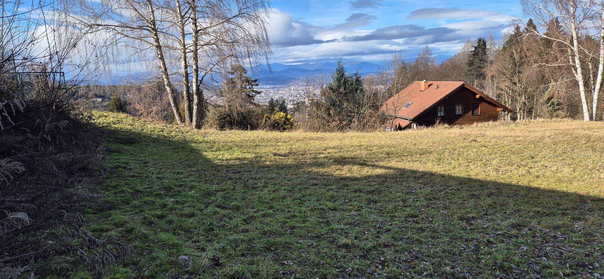 Weitläufige Grünfläche mit Blick auf die umliegende Landschaft und ein Haus im Hintergrund.