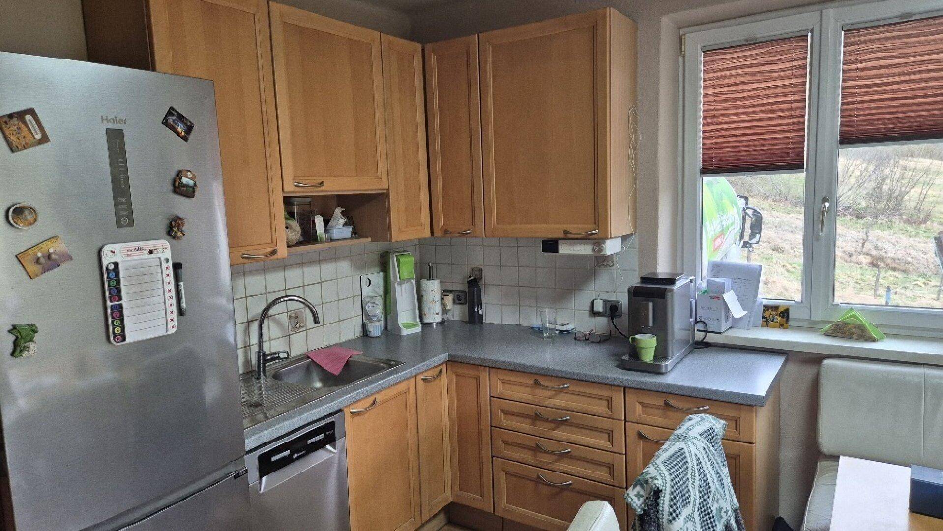 Funktionale Küche mit Holzschränken, Spülbecken und Kühlschrank, ausgestattet für den Alltag.