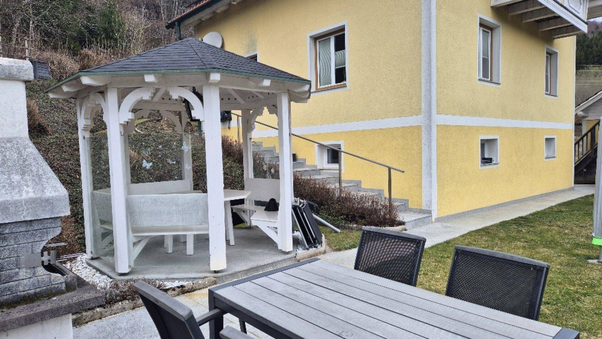 Gemütlicher Gartenbereich mit Esstisch, Stühlen und einem weißen Pavillon für entspannte Stunden.