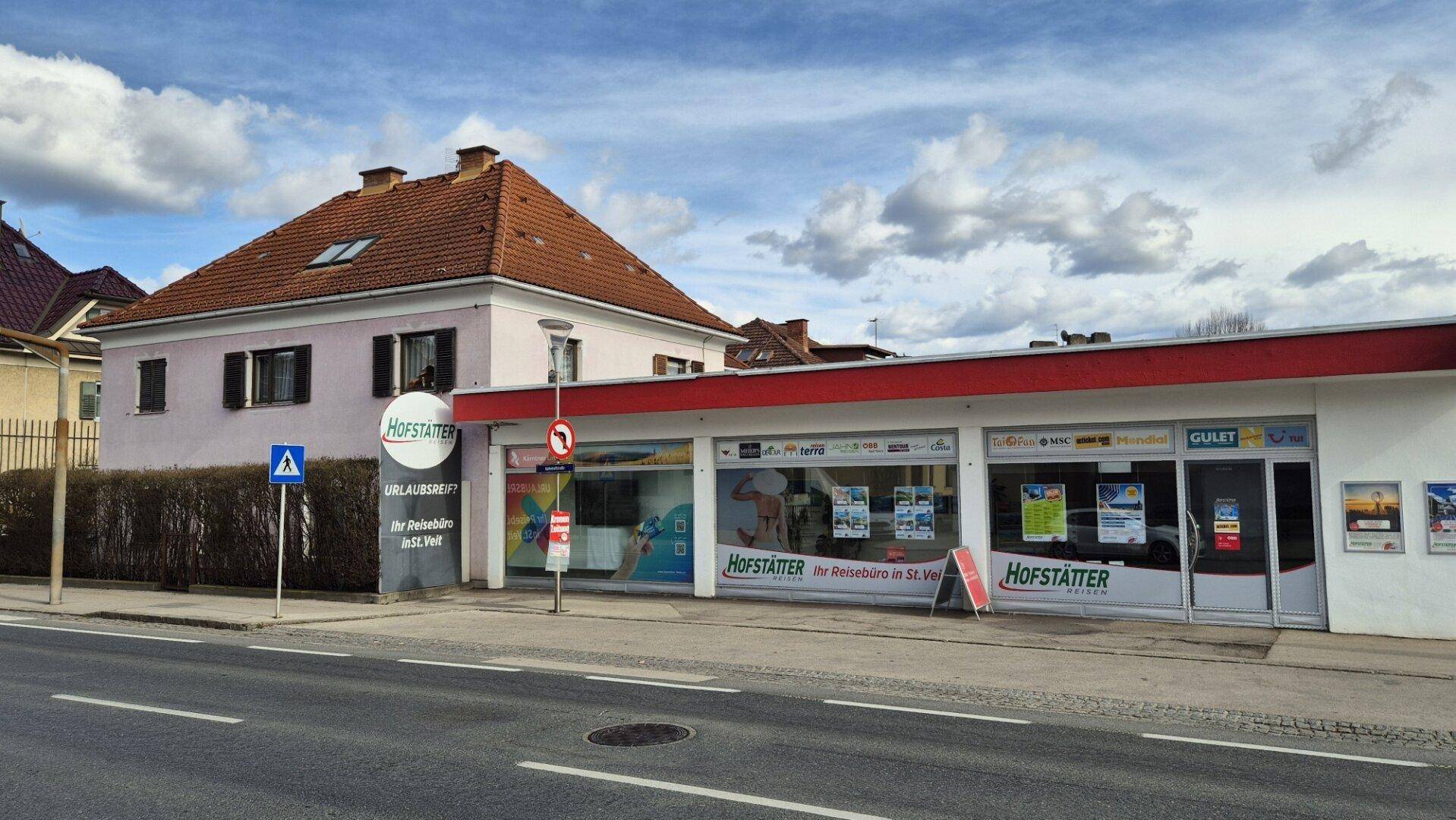 Seitenansicht des Gebäudes mit rotem Ziegeldach und dem angrenzenden Geschäft Hofstätter.