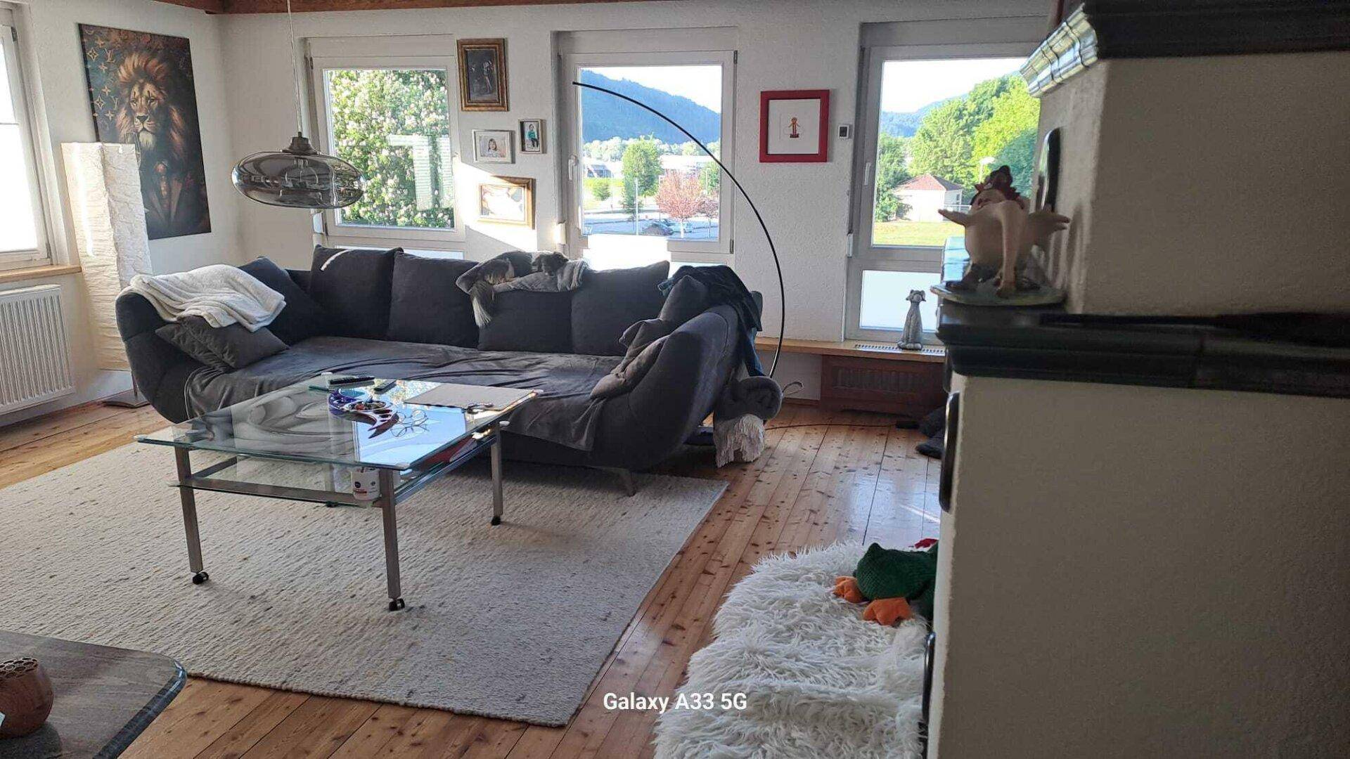 Gemütliches Wohnzimmer mit großem Sofa, Holzboden und Blick auf die Berge.