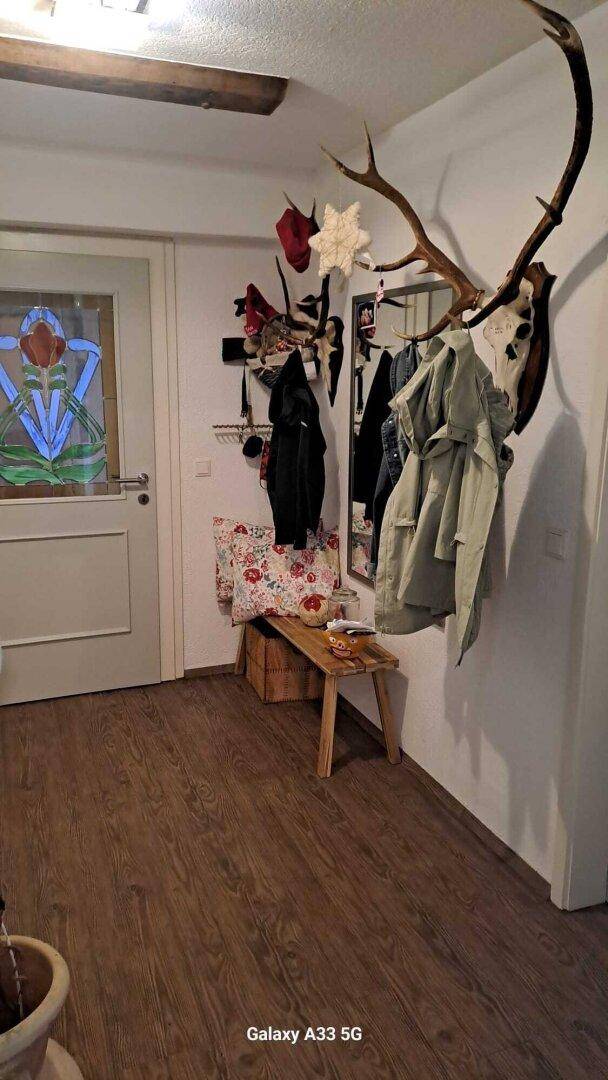 Eingangsbereich mit Holzboden, Garderobe und Hirschgeweih-Dekoration an der Wand.