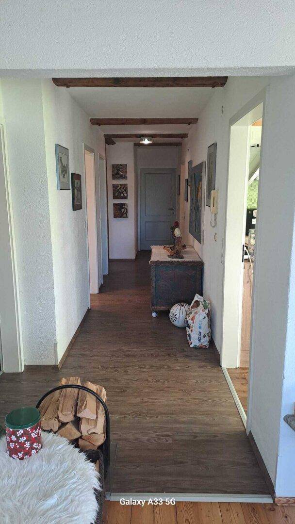 Langer Flur mit Holzbalken an der Decke und dunklem Holzboden.
