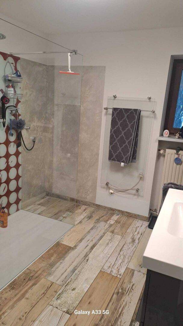 Modernes Badezimmer mit begehbarer Dusche, Holzbodenoptik und Handtuchheizkörper.