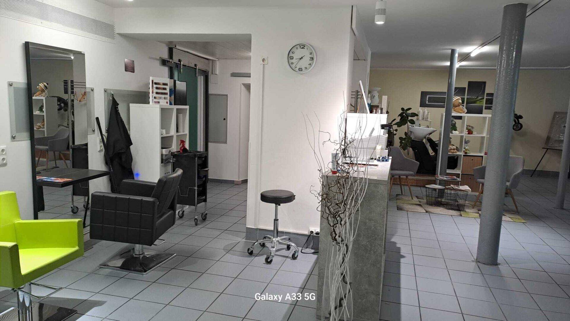 Friseursalon mit mehreren Arbeitsplätzen, Spiegeln und Fliesenboden.