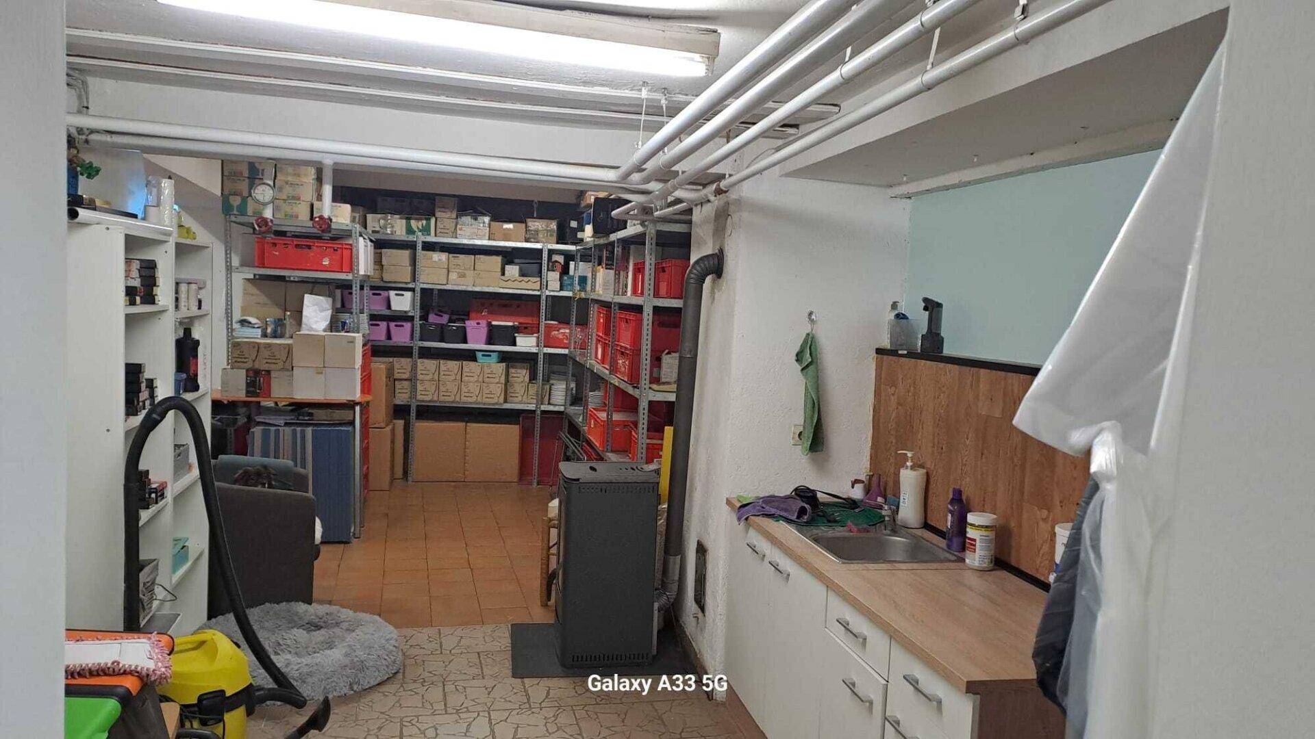 Geräumiger Abstellraum im Keller mit Regalen, Waschbecken und Heizofen.