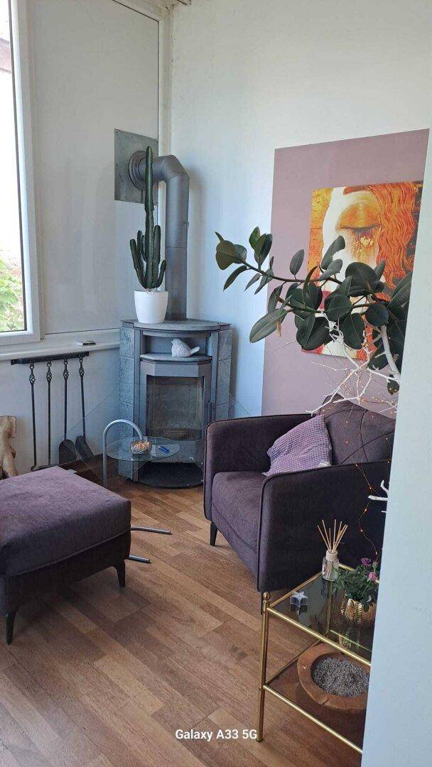 Gemütliche Sitzecke mit Holzboden, Kaminofen und einem Sessel in dunklem Lila.