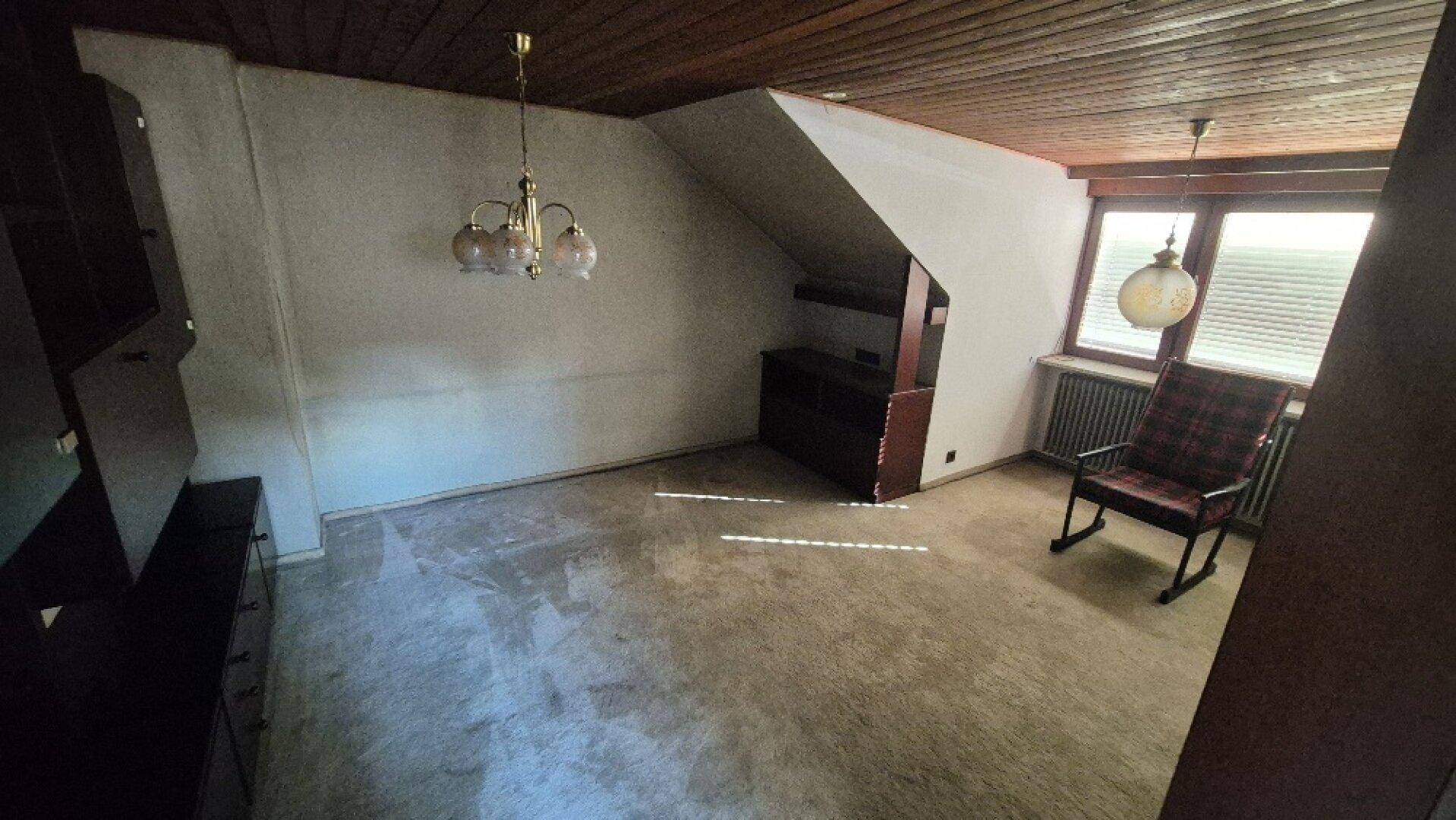 Dachgeschossraum mit Holzdecke, Teppichboden und schrägen Wänden, bietet gemütliches Ambiente.