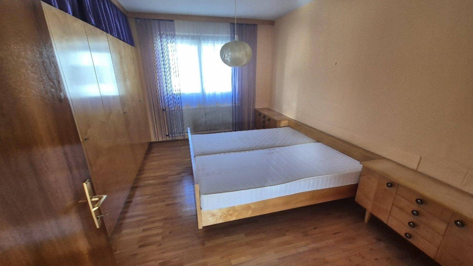 Helles Schlafzimmer mit zwei Einzelbetten, Holzschrank und Parkettboden, ideal für Gäste.