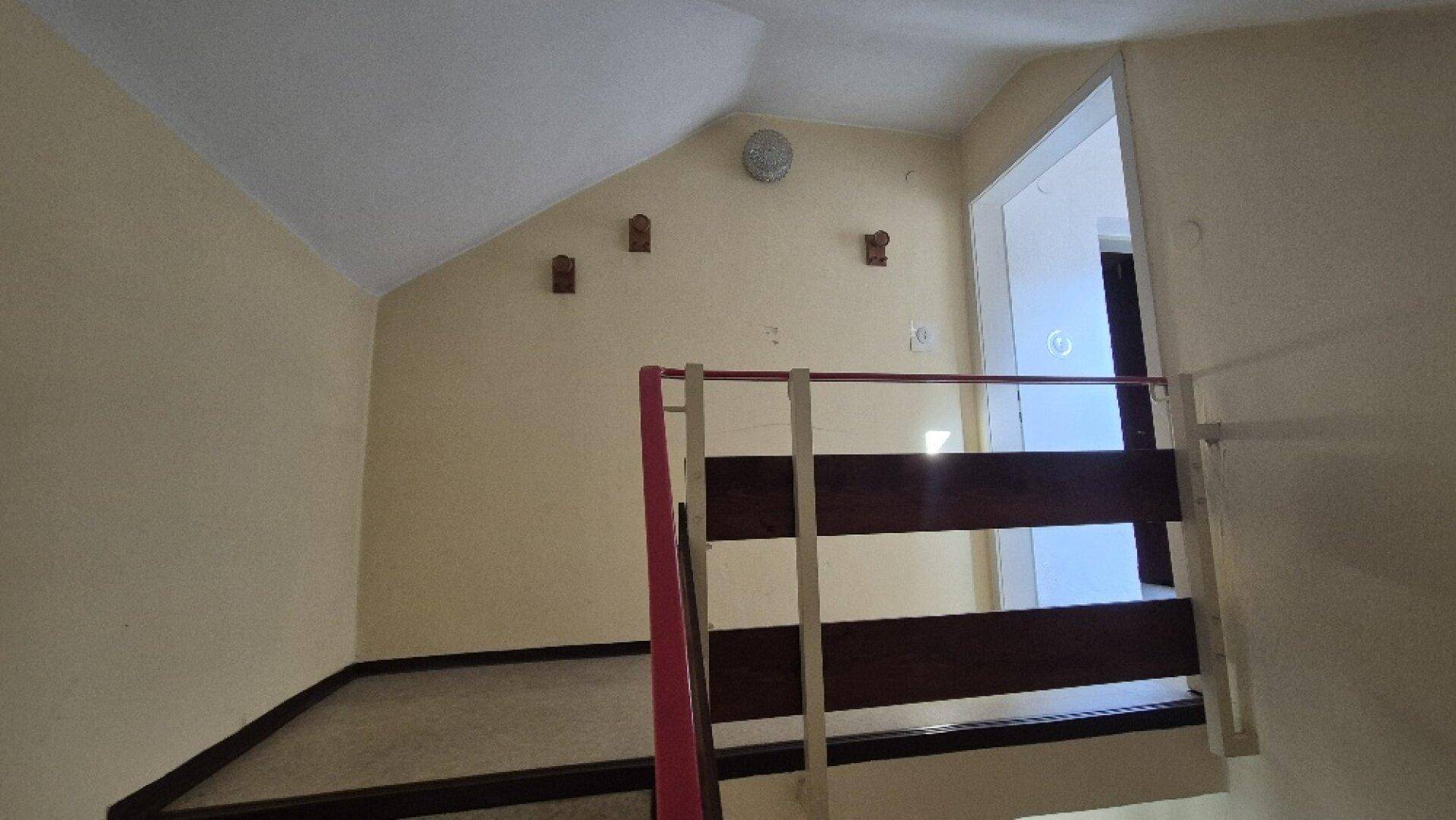 Heller Treppenabsatz im Dachgeschoss mit schrägen Wänden und Holzgeländer, gut beleuchtet.