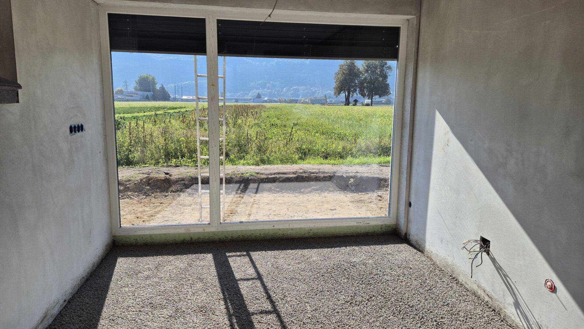 Heller Rohbau-Raum mit weitem Ausblick auf die Natur und die Bergkette.