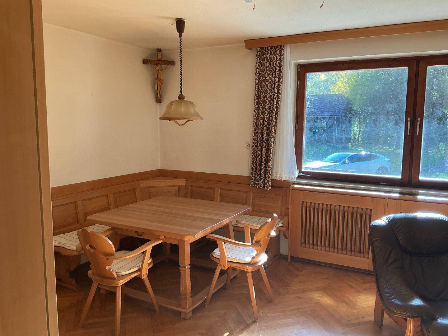 Heller Essbereich mit traditionellen Holzmöbeln und Eckbank, mit Blick ins Grüne.