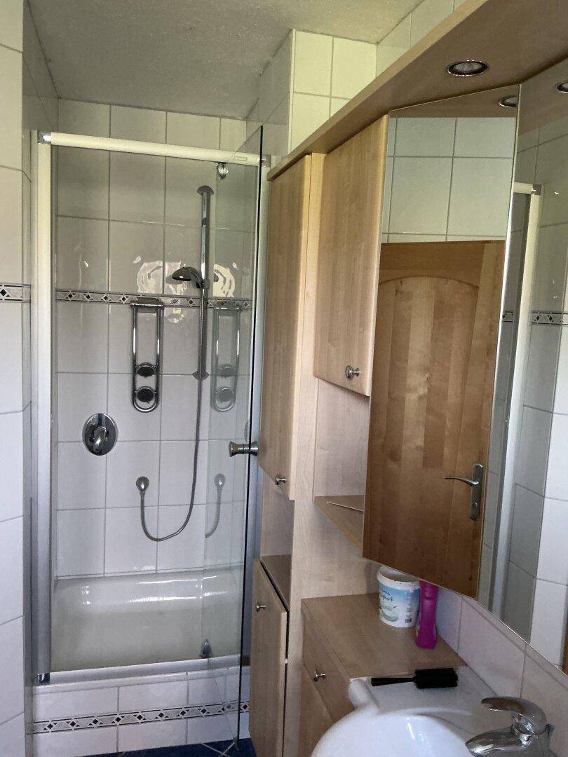 Badezimmer mit Duschbadewanne, Spiegelschrank und hellen Fliesen.