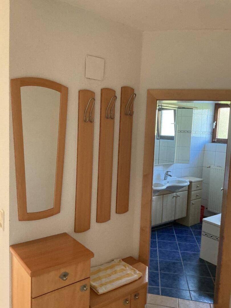 Eingangsbereich mit Garderobe und Blick in das angrenzende Badezimmer.