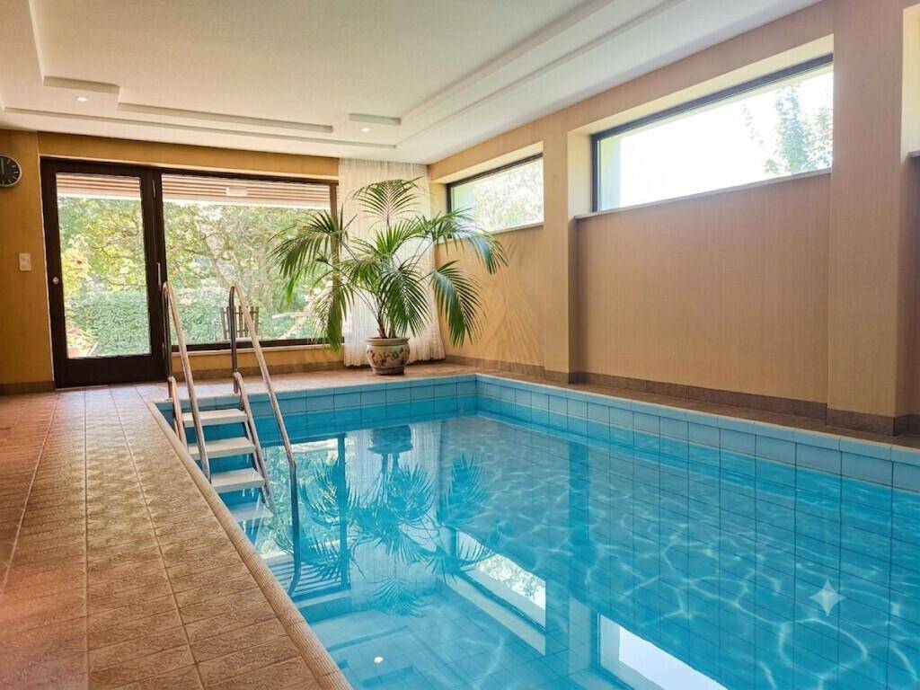 Innenpoolbereich mit großen Fenstern, viel Tageslicht und direktem Zugang zum Garten.