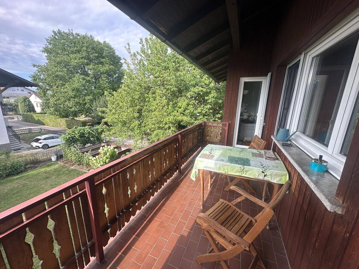 Gemütlicher Balkon mit Holztisch und Stühlen, ideal für entspannte Stunden im Freien.