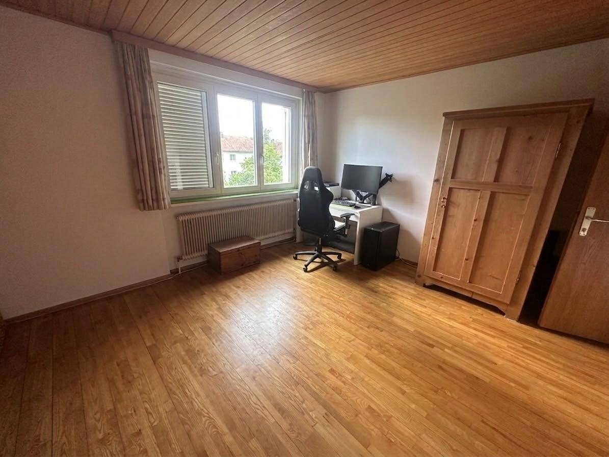 Schlafzimmer mit Holzboden, Schreibtisch und großem Kleiderschrank.