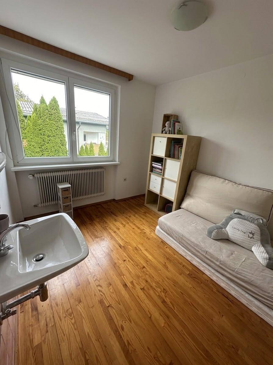 Heller Raum mit Waschbecken, kleiner Couch und Holzboden.