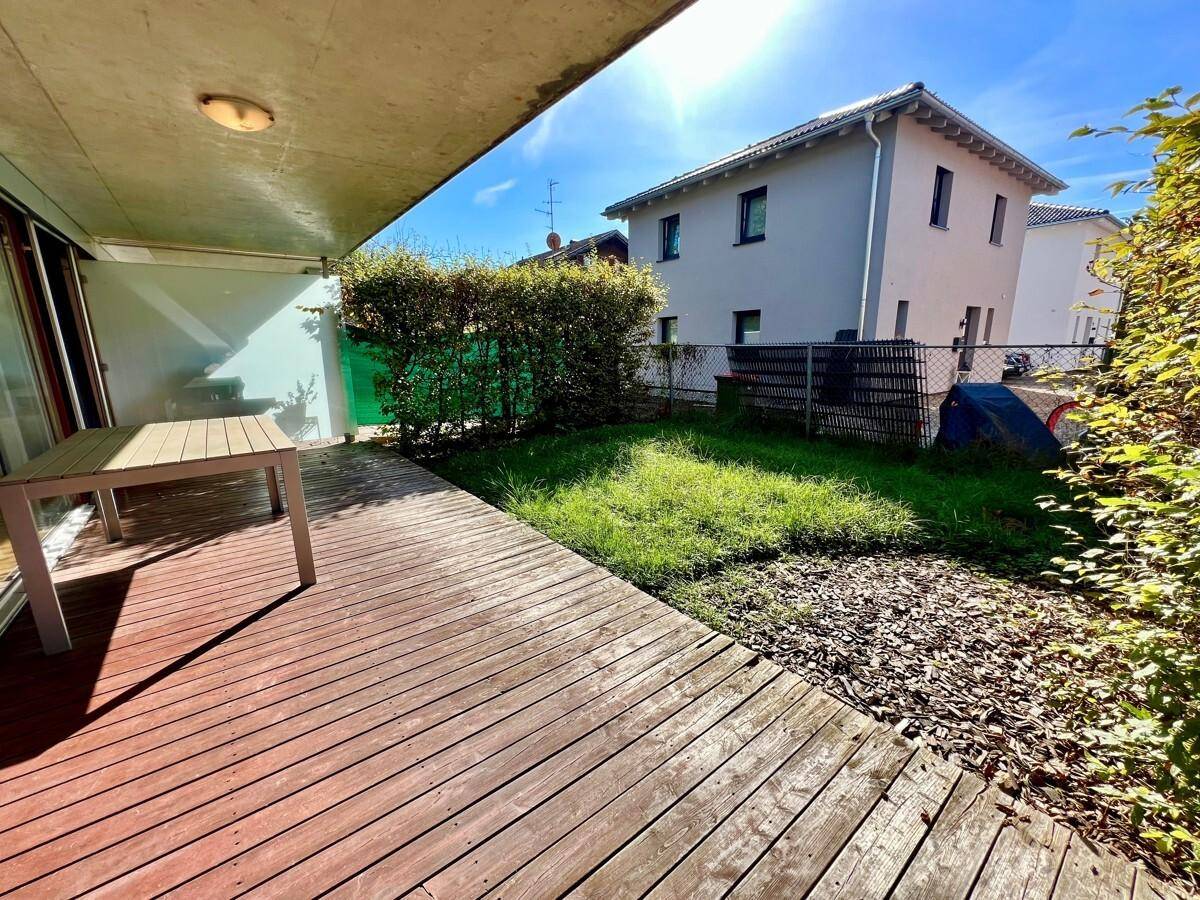Sonniger Terrassenbereich mit Holzdeck und kleinem Rasenstück, ideal für Entspannung im Freien.