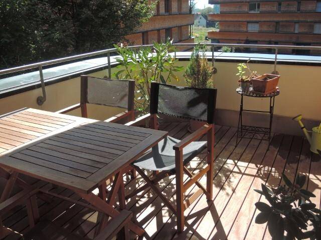 Möblierter Balkon mit Holzboden, Esstisch und Stühlen, ideal für entspannte Stunden im Freien.