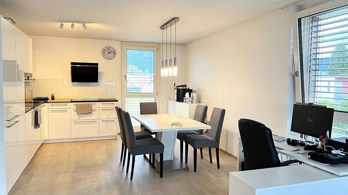 Offene Küche und Essbereich mit hellem Esstisch, modernen Schränken und einem Arbeitsplatz am Fenster.