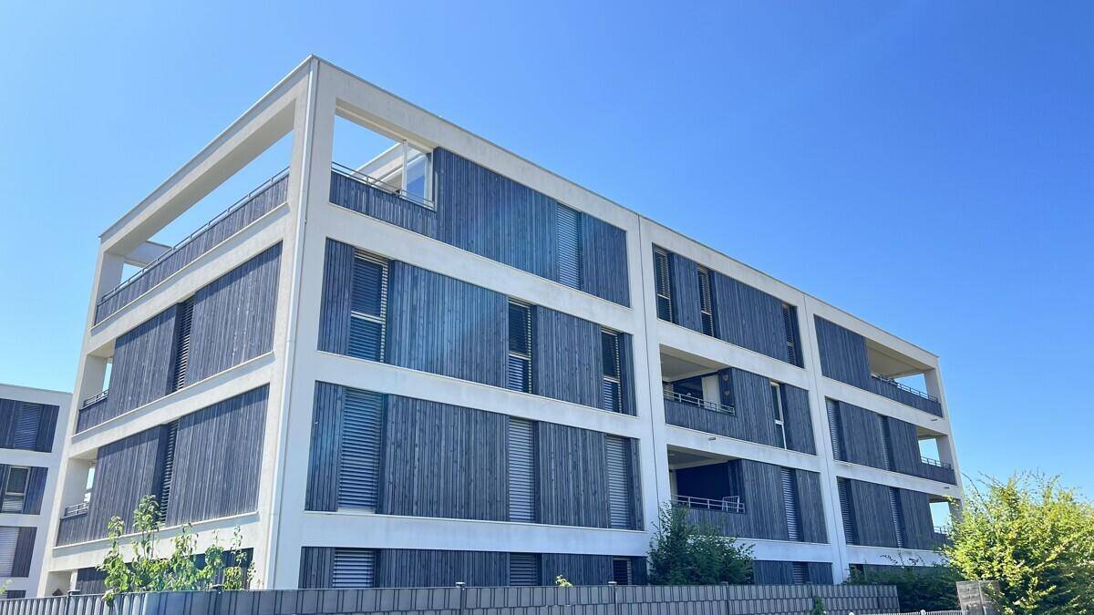 Moderne Architektur des Wohngebäudes mit klaren Linien und attraktiven Balkonen unter blauem Himmel.
