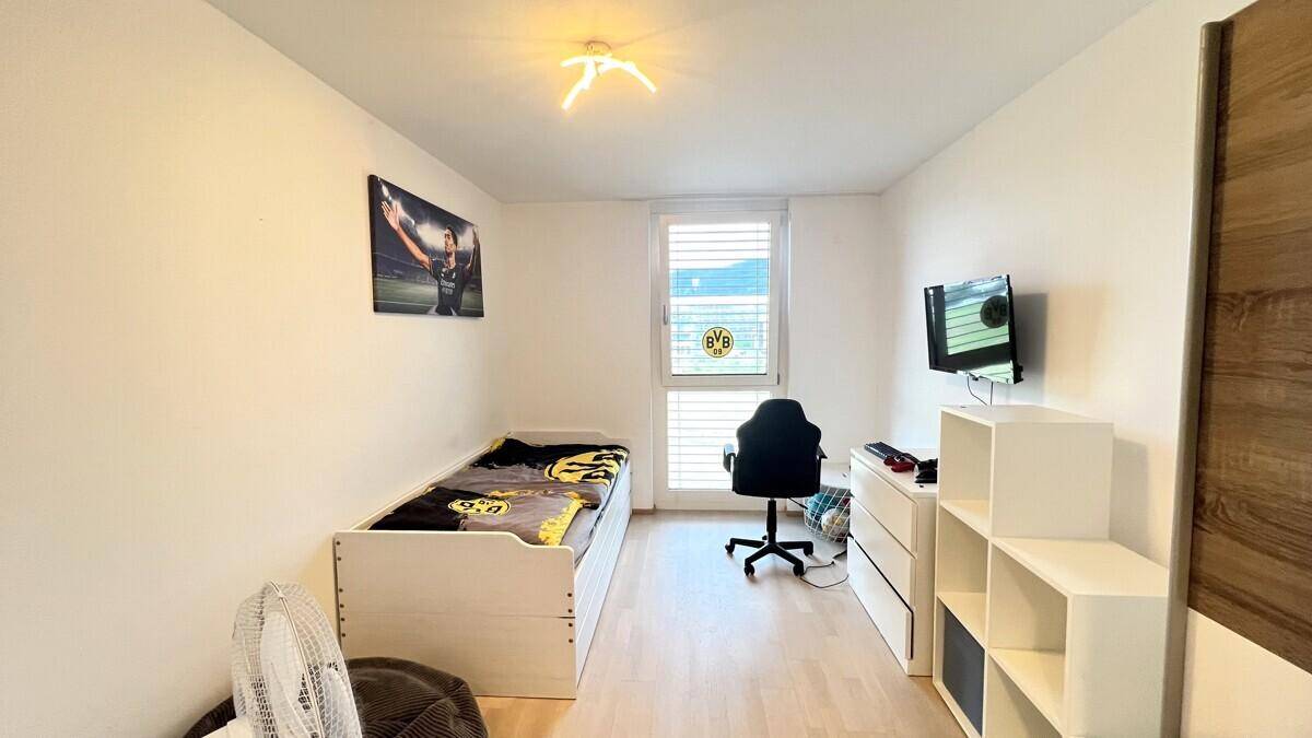 Kinder- oder Gästezimmer mit Einzelbett, Schreibtisch und Regal, ideal für junge Bewohner oder Besucher.