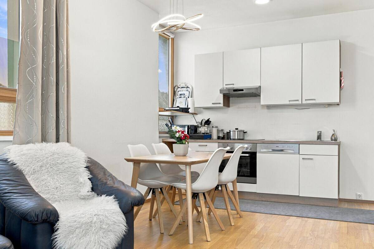 Moderne Einbauküche mit weißen Schränken, Essbereich und Blick ins Grüne.