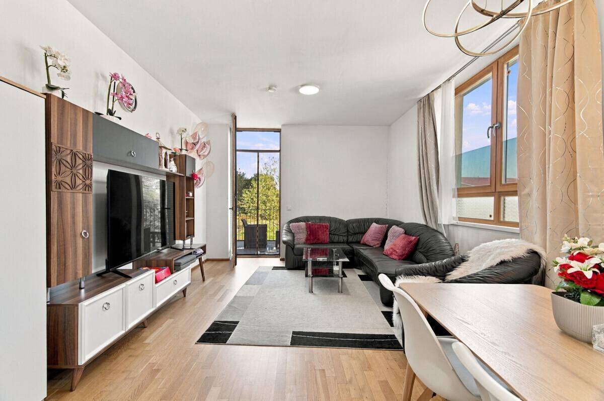 Geräumiger Wohn-Essbereich mit Holzboden, bequemer Sitzecke und Zugang zum Balkon.