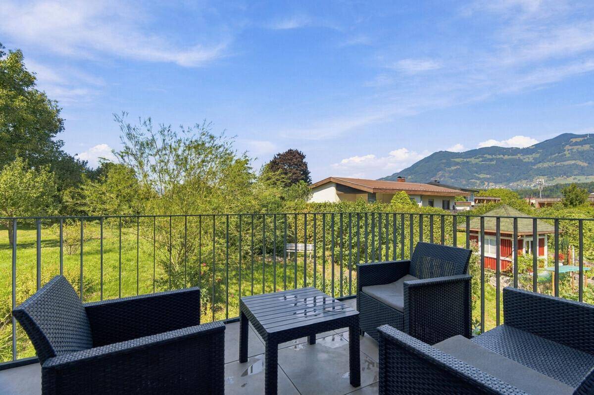Großer Balkon mit Sitzgelegenheiten und weitem Blick auf die grüne Landschaft und Berge.