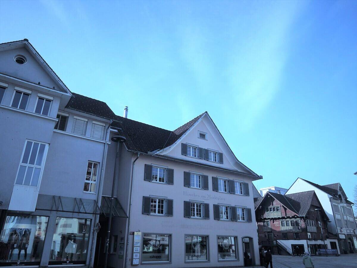 Reihe von historischen Gebäuden mit Geschäften und Wohnungen unter einem klaren blauen Himmel.
